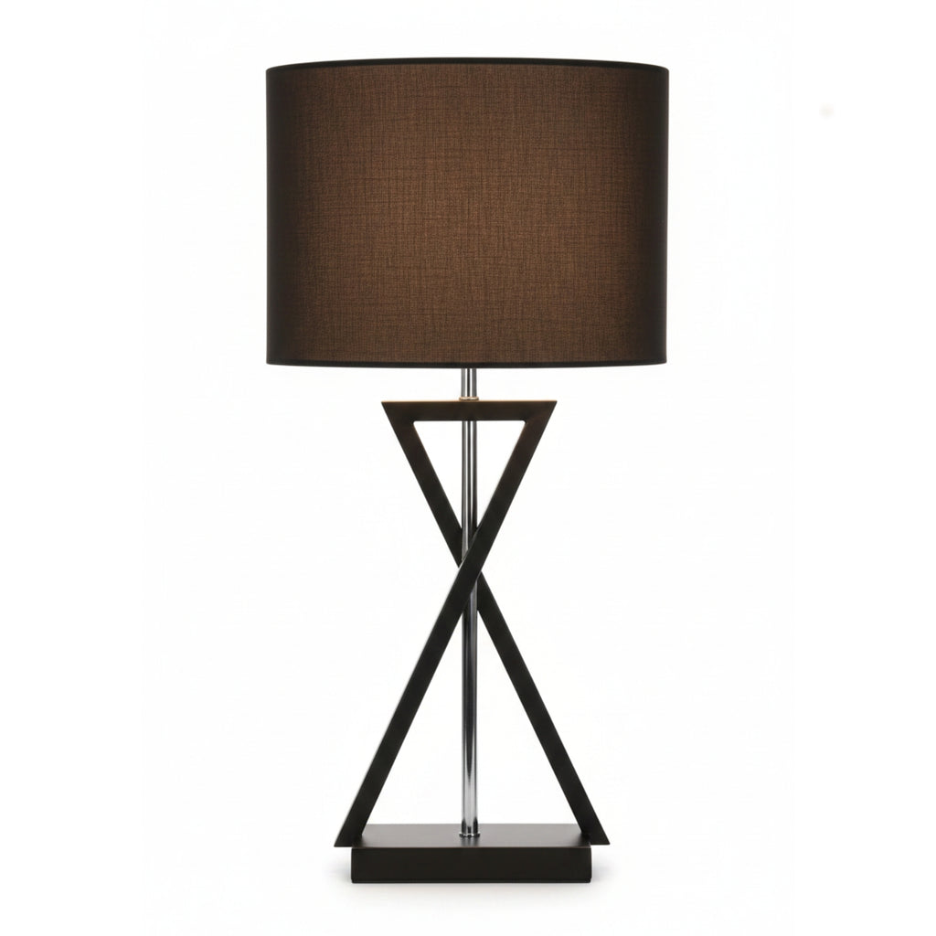 A table lamp with a dark brown fabric drum shade and a black metal base featuring an intersecting triangular design and a clear central stem, shown against a plain white background.