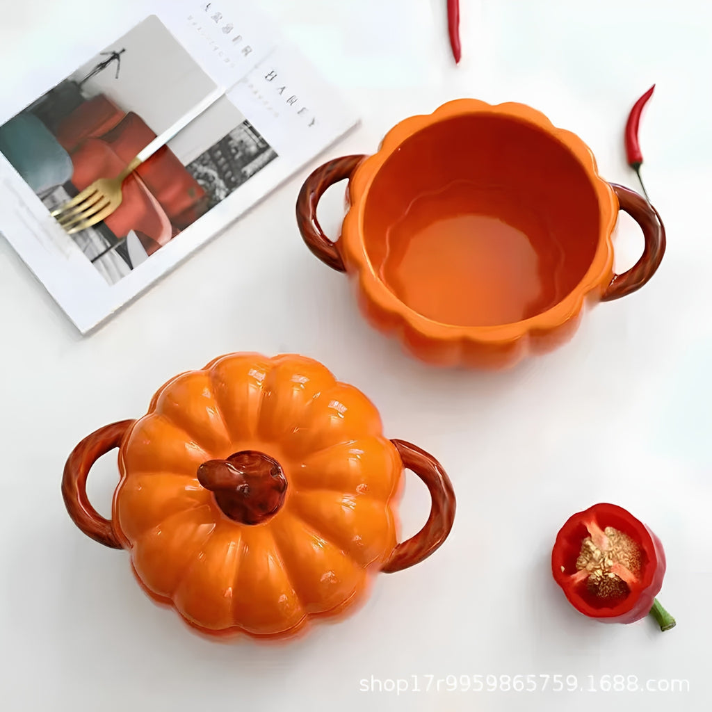 Two pumpkin-shaped ceramic bowls with brown handles, one shown open and one with the lid on, arranged on a white surface with decorative red chili peppers and a magazine.