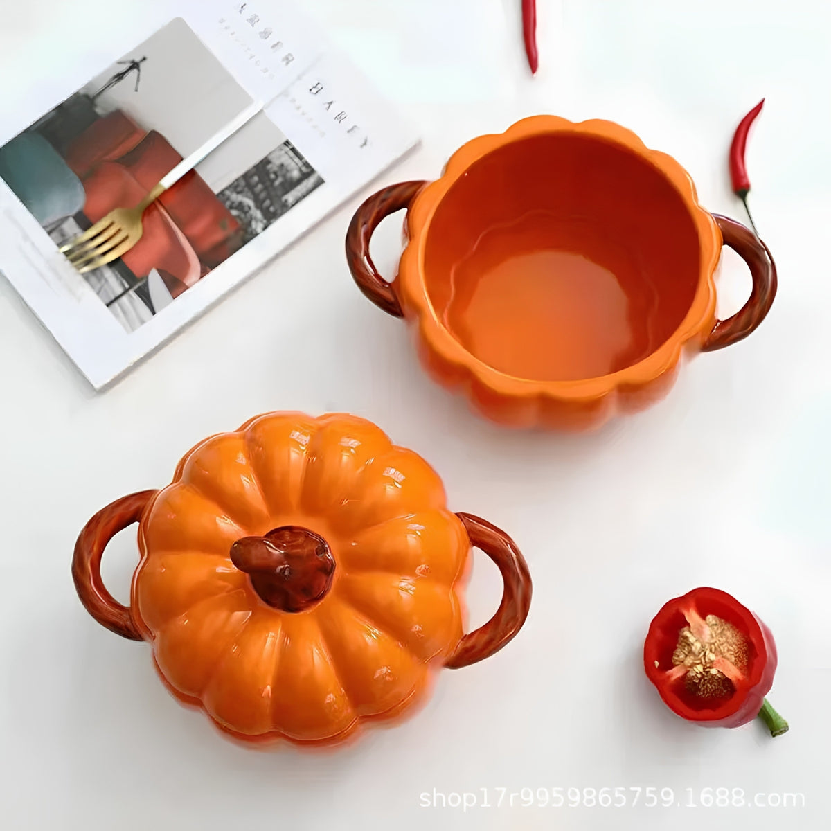Two pumpkin-shaped ceramic bowls with brown handles, one shown open and one with the lid on, arranged on a white surface with decorative red chili peppers and a magazine.