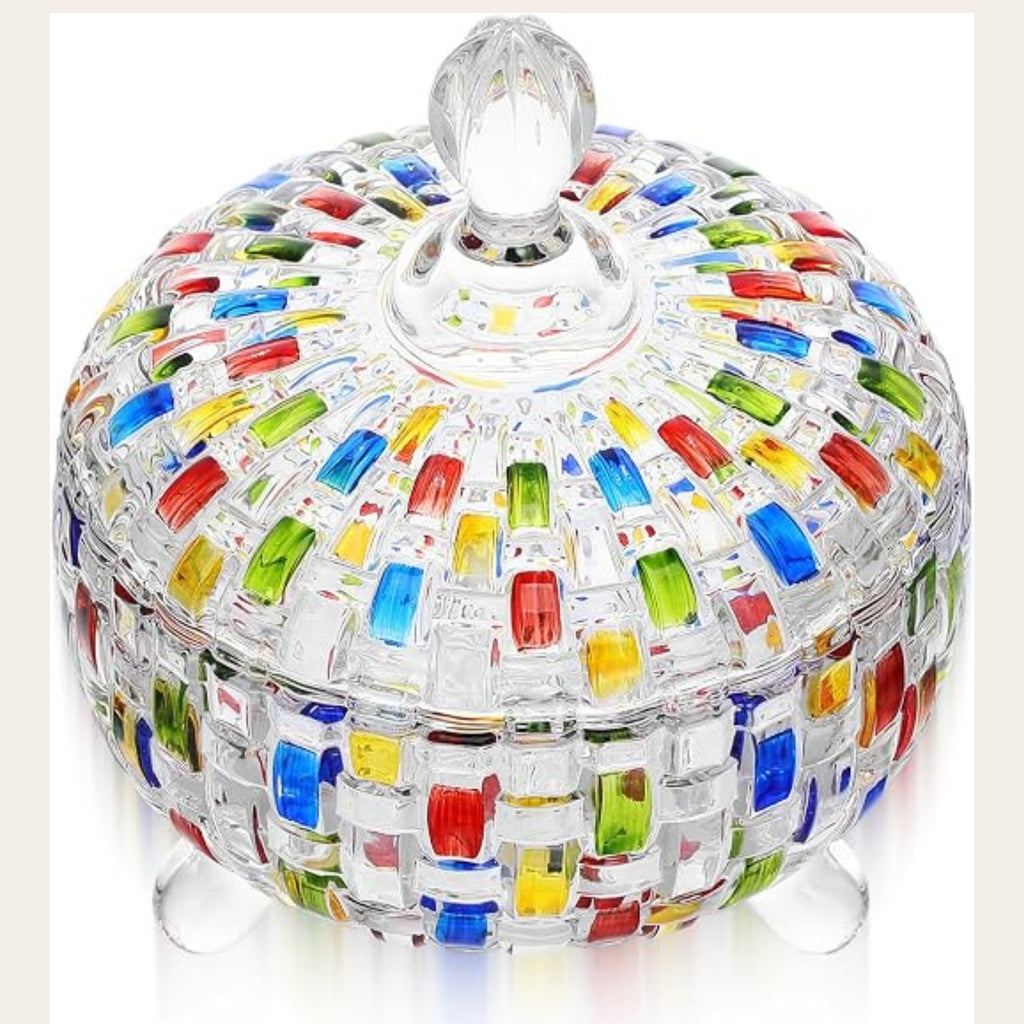 A clear glass lidded box with a colorful mosaic pattern of red, blue, green, yellow, and orange glass pieces, standing on small clear glass feet against a white background.