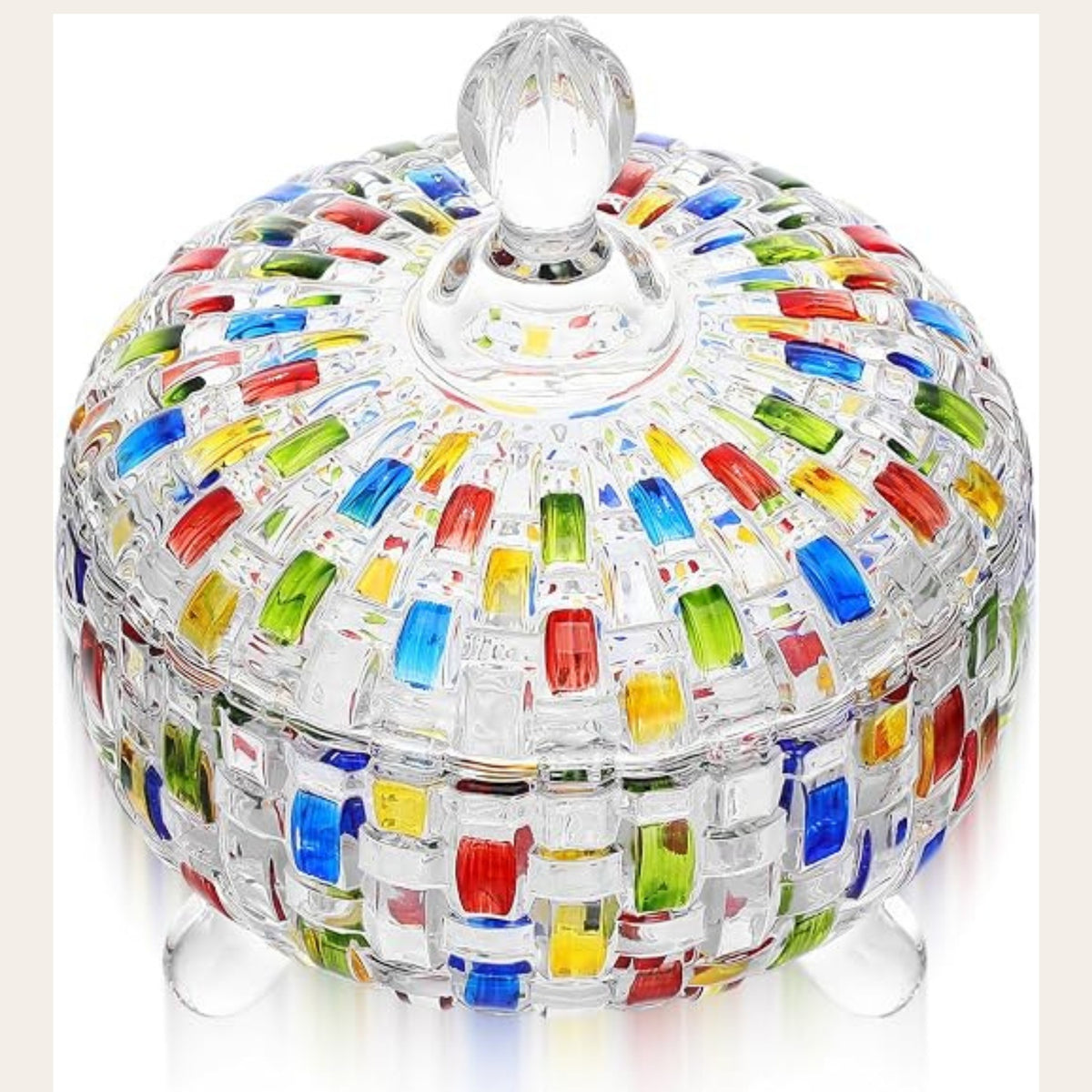 A clear glass lidded box with a colorful mosaic pattern of red, blue, green, yellow, and orange glass pieces, standing on small clear glass feet against a white background.