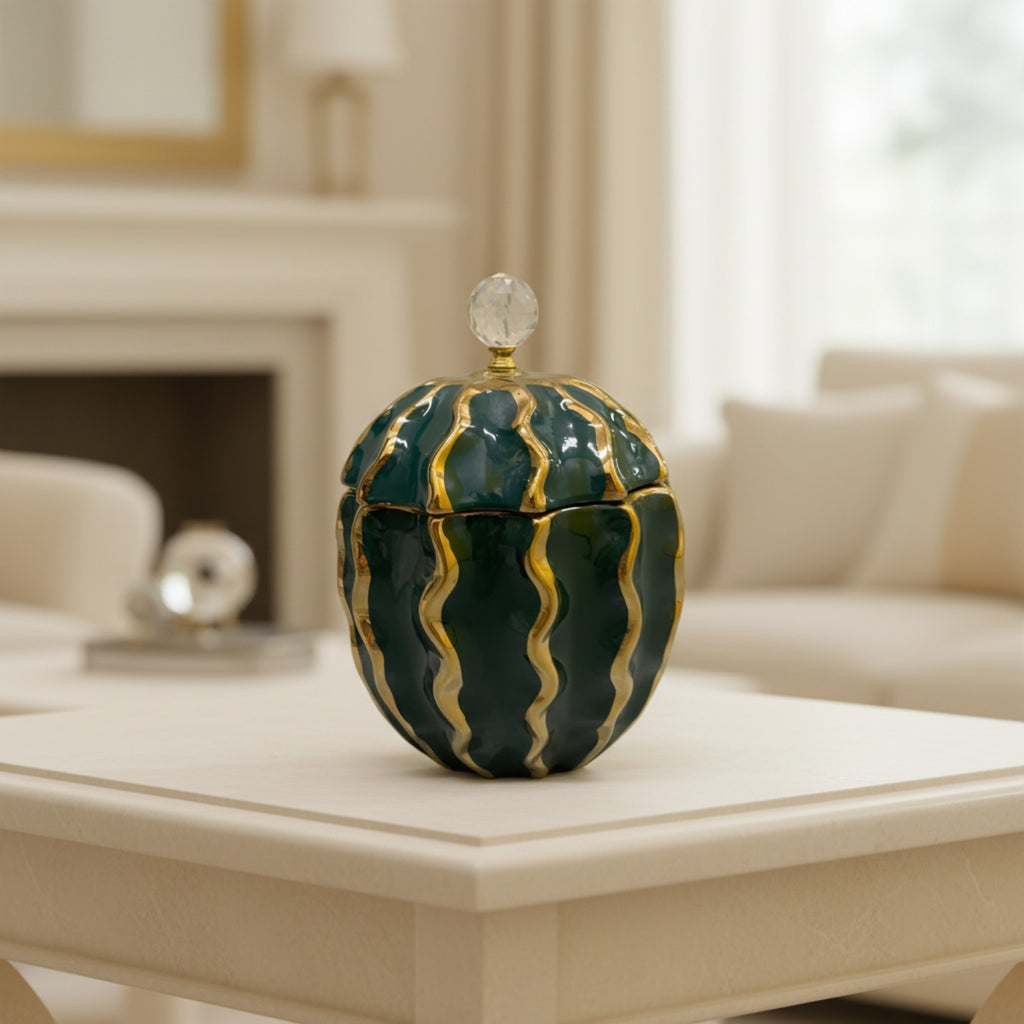 A decorative lidded ceramic jar with a deep green and gold wavy pattern, set on a cream-colored table in a softly blurred living room background.