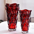 Two red glass vase-like containers with wavy scalloped rims and an embossed bubble pattern, displayed on a white surface against a soft light gray background.