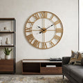 A large round wall clock with a natural wood frame and Roman numerals hangs on a textured off-white wall in a modern living room setting.