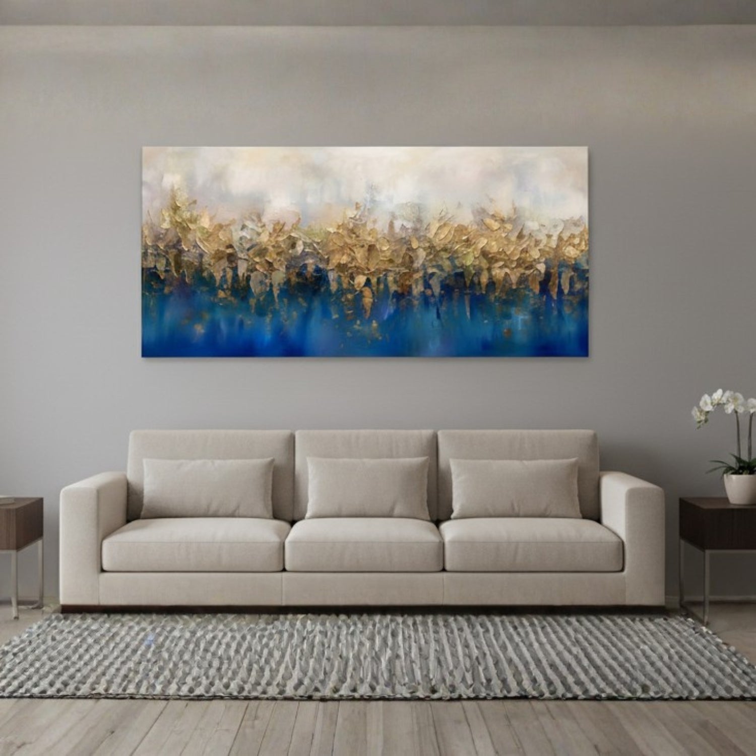A large rectangular abstract canvas print with blue water-like lower sections and shimmering gold brushstrokes across the top, displayed above a light beige sofa in a modern living room setting.