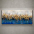 A wide rectangular abstract canvas painting mounted on a textured gray wall. The artwork features a soft cream and beige upper section blending into a deep blue lower section, with layered brushstrokes and reflective gold-like highlights across the center.