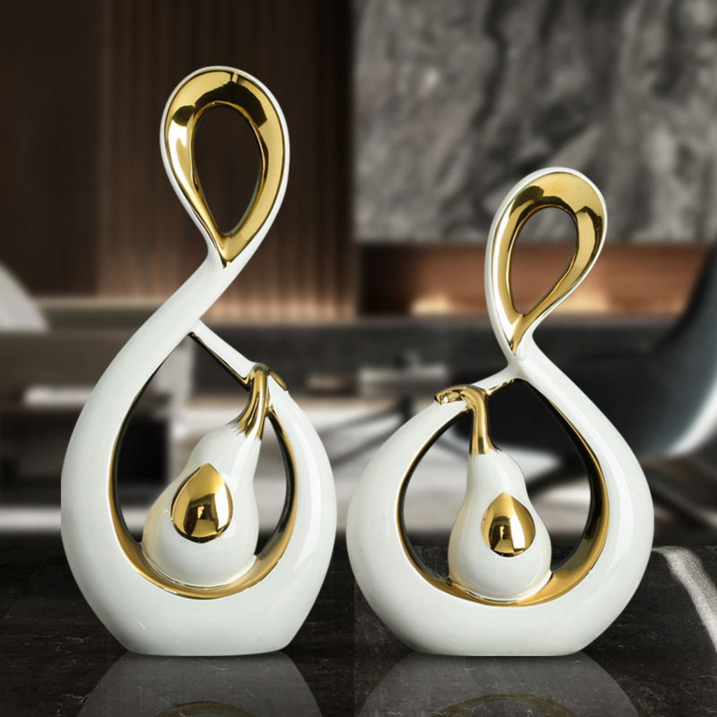 Two decorative ceramic pieces with gold accents on a reflective surface.