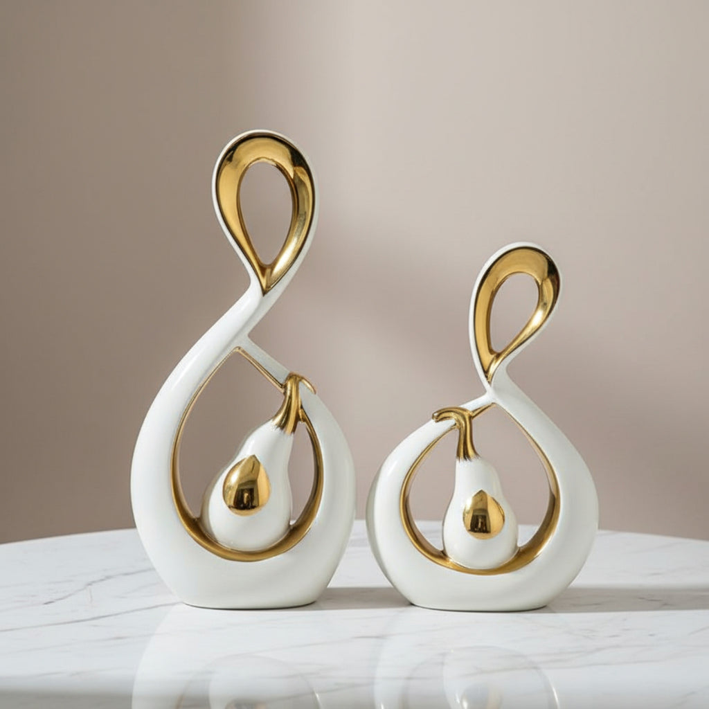 Two modern white and gold decorative swan figurines displayed on a white marble surface against a soft beige background.