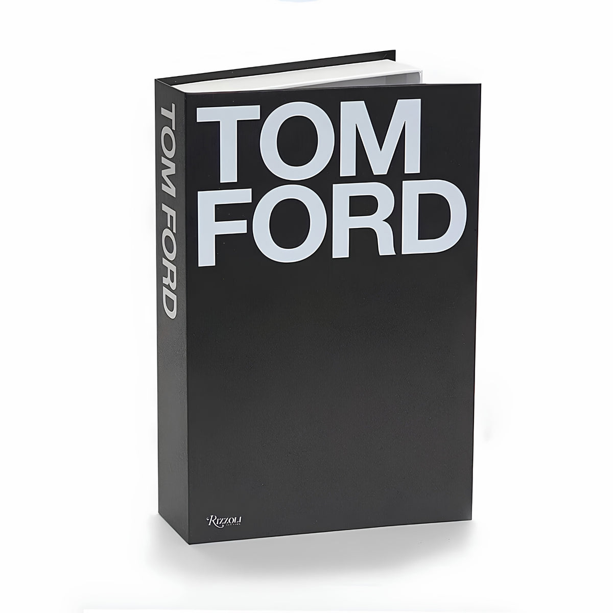 A hardcover book titled 'TOM FORD' with a matte black cover and bold white lettering, standing upright on a white background.