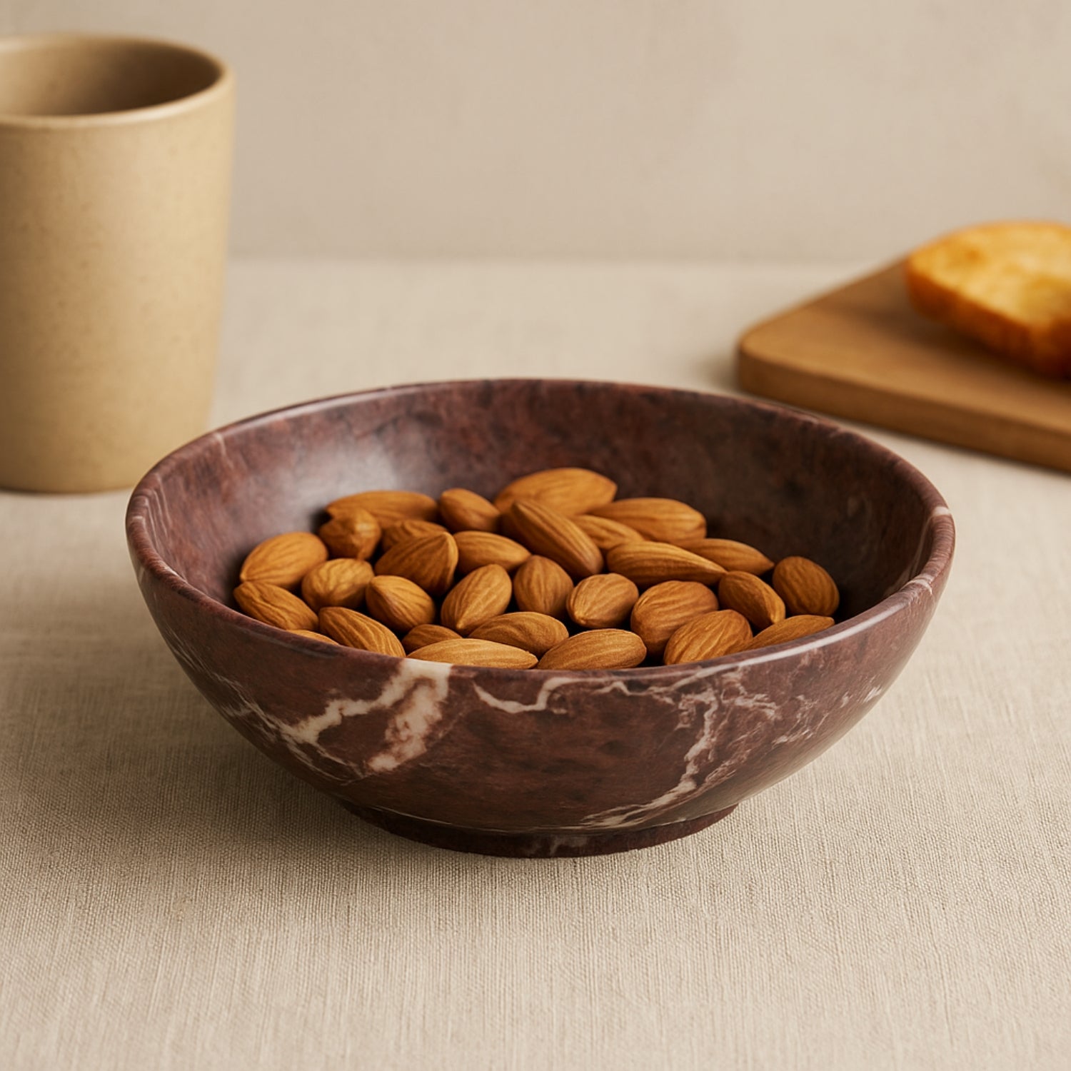 Marble-patterned bowl filled with almonds on a neutral background