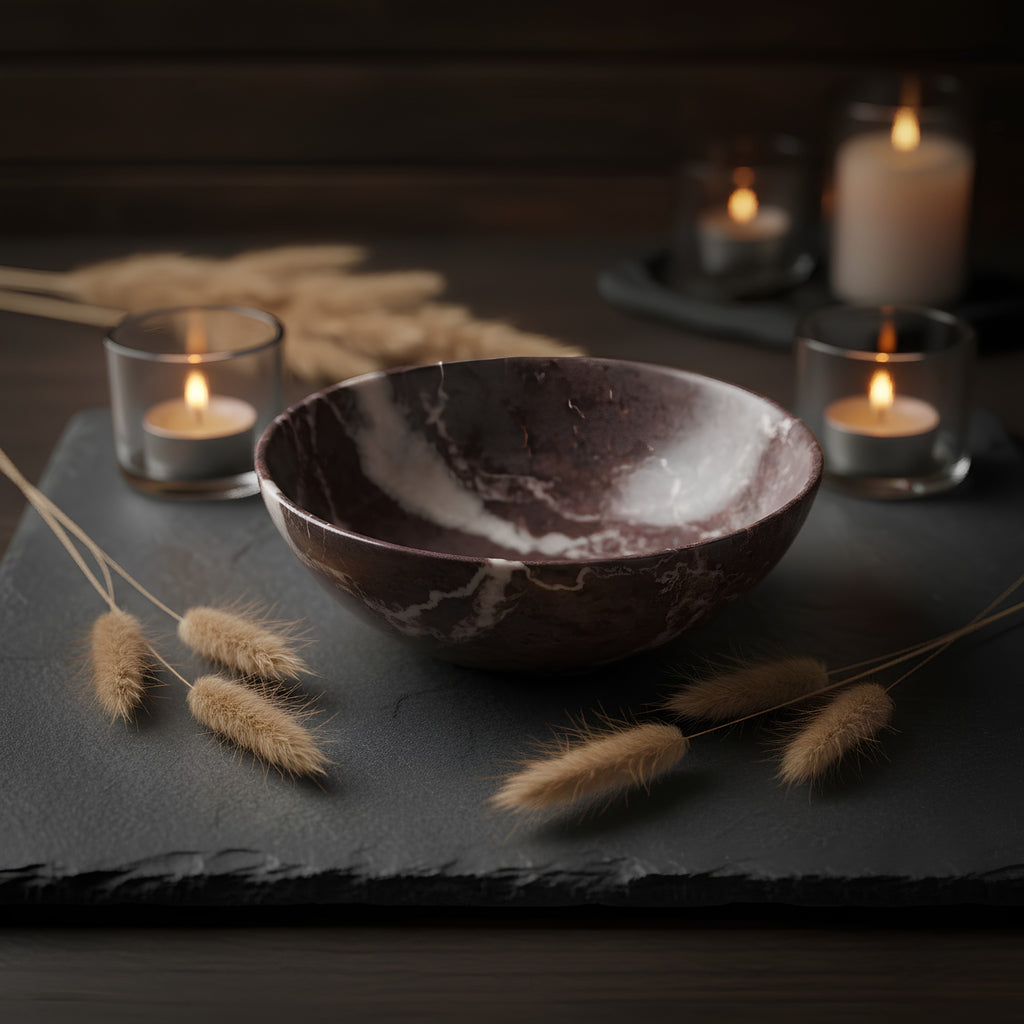 A handmade stone bowl with a reddish-brown and white marbled pattern, resting on a textured brown paper background.