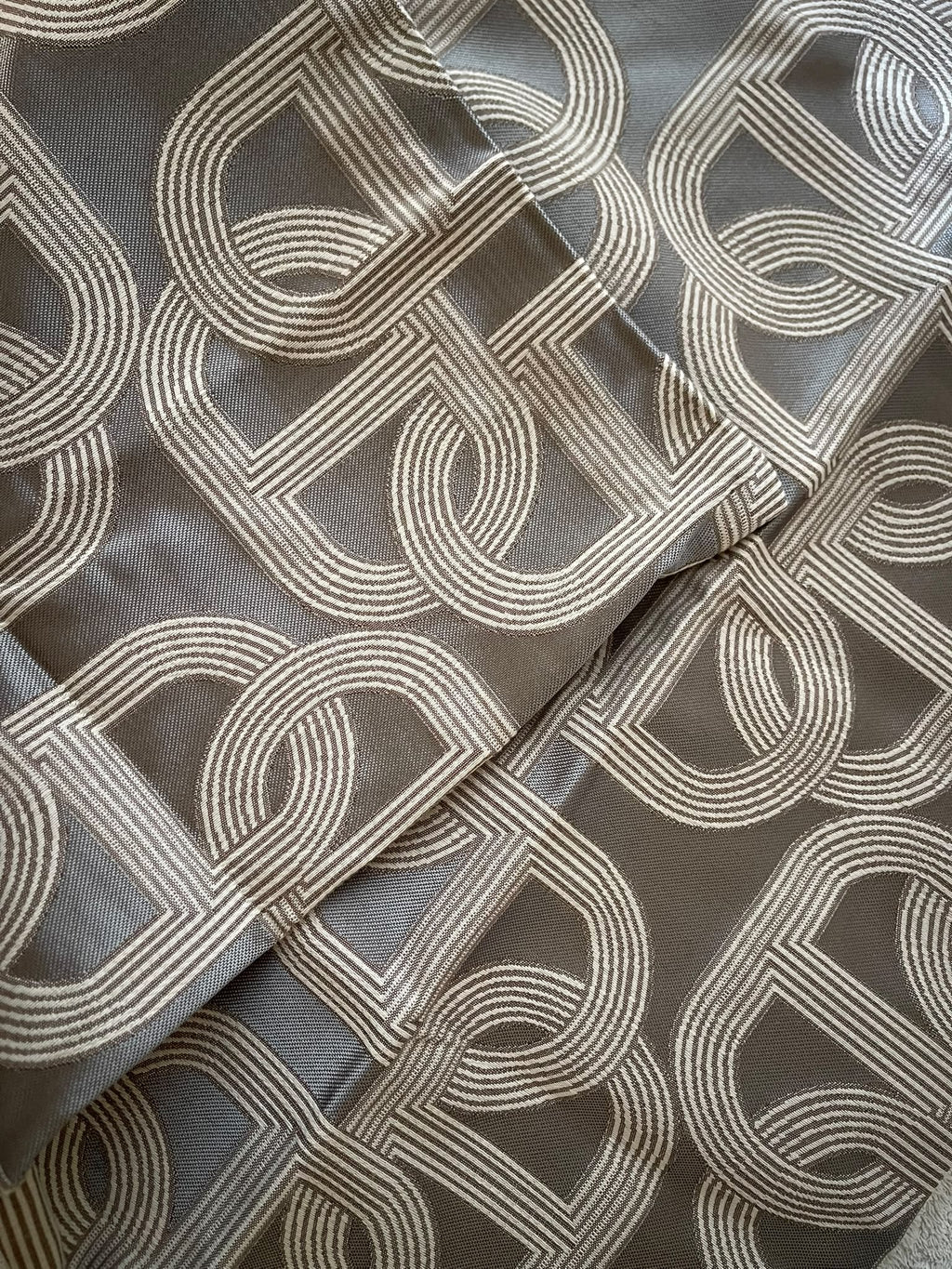 Close-up of grey fabric with contrasting interlocking chain link pattern