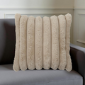 Tan plush velvet square cushion with raised vertical lines on a sofa